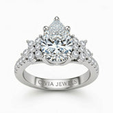 White Gold Pear Cut Engagement Ring With Floral Diamond Cluster Sides And Pavé Band
