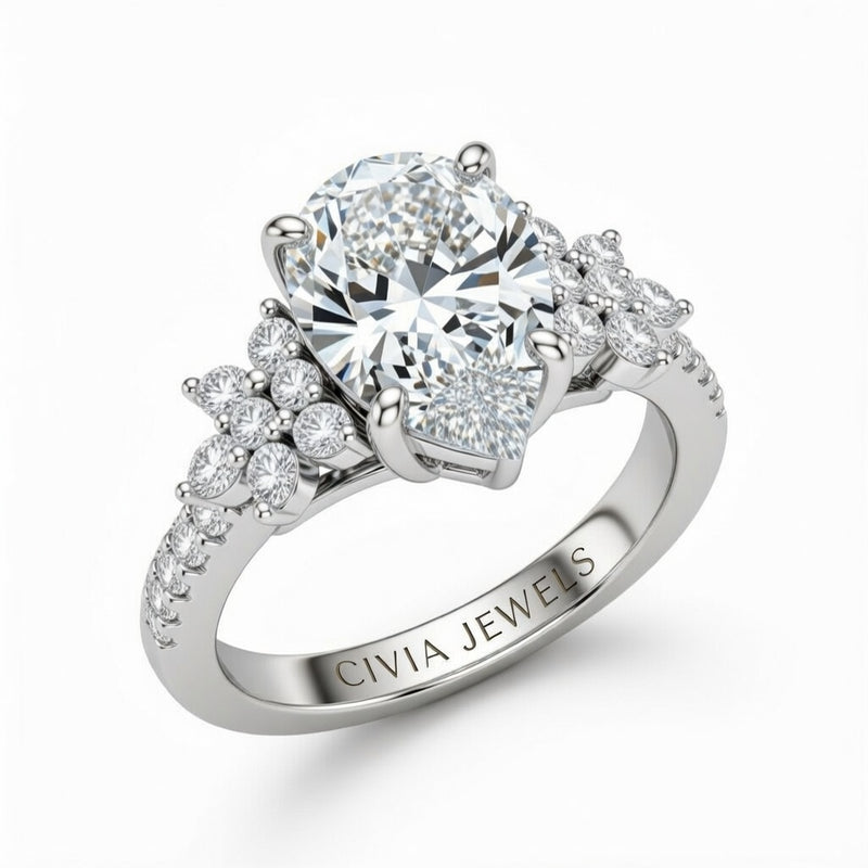 White Gold Pear Cut Engagement Ring With Floral Diamond Cluster Sides And Pavé Band